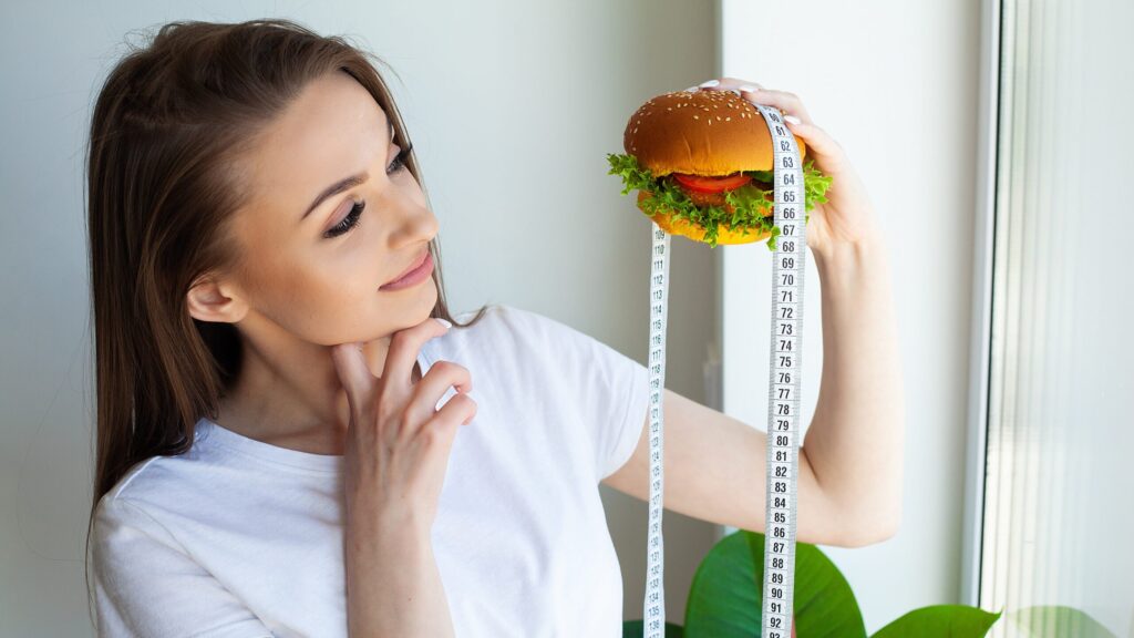 Kobieta na zdjęciu zastanawia się, ile kalorii dziennie jeść, żeby schudnąć.