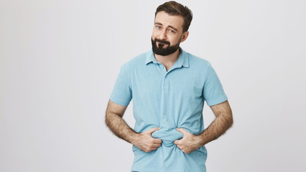 Mężczyzna na zdjęciu zastanawia się, jak schudnąć z brzucha.