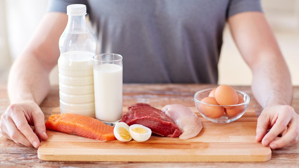 Mężczyzna na zdjęciu ma na desce drewnianej wszystko to, co ma dużo białka.